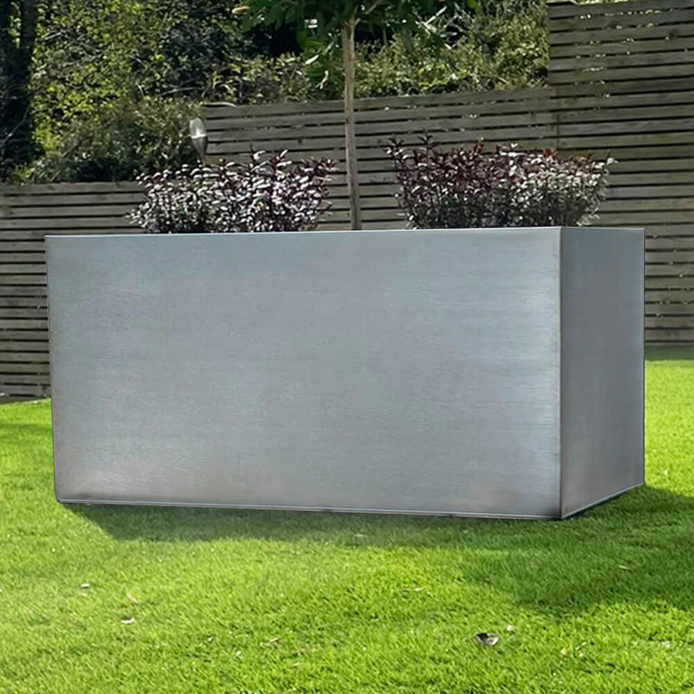 A large rectangular black zinc trough patio planter placed on a grassy area with a wooden fence in the background. The planter is empty and has a reflective surface.