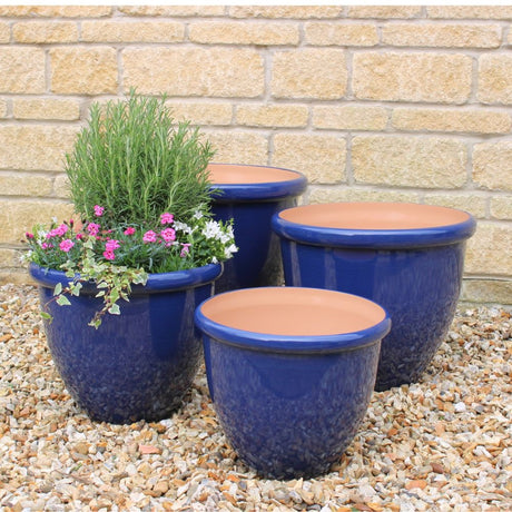 Blue ceramic plant pots in garden on gravel