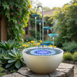 Outdoor garden fountain with blue tiers and white base in a garden setting