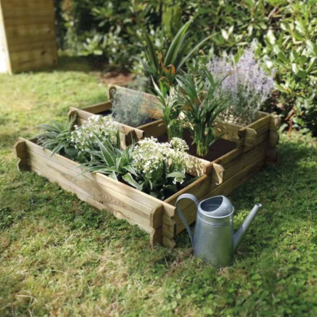 Wooden raised garden bed with plants and a watering can on grass