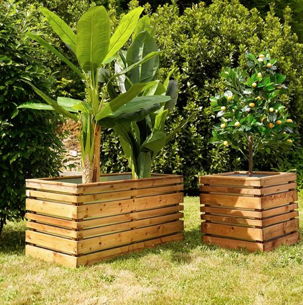Two wooden planters with plants in a garden setting