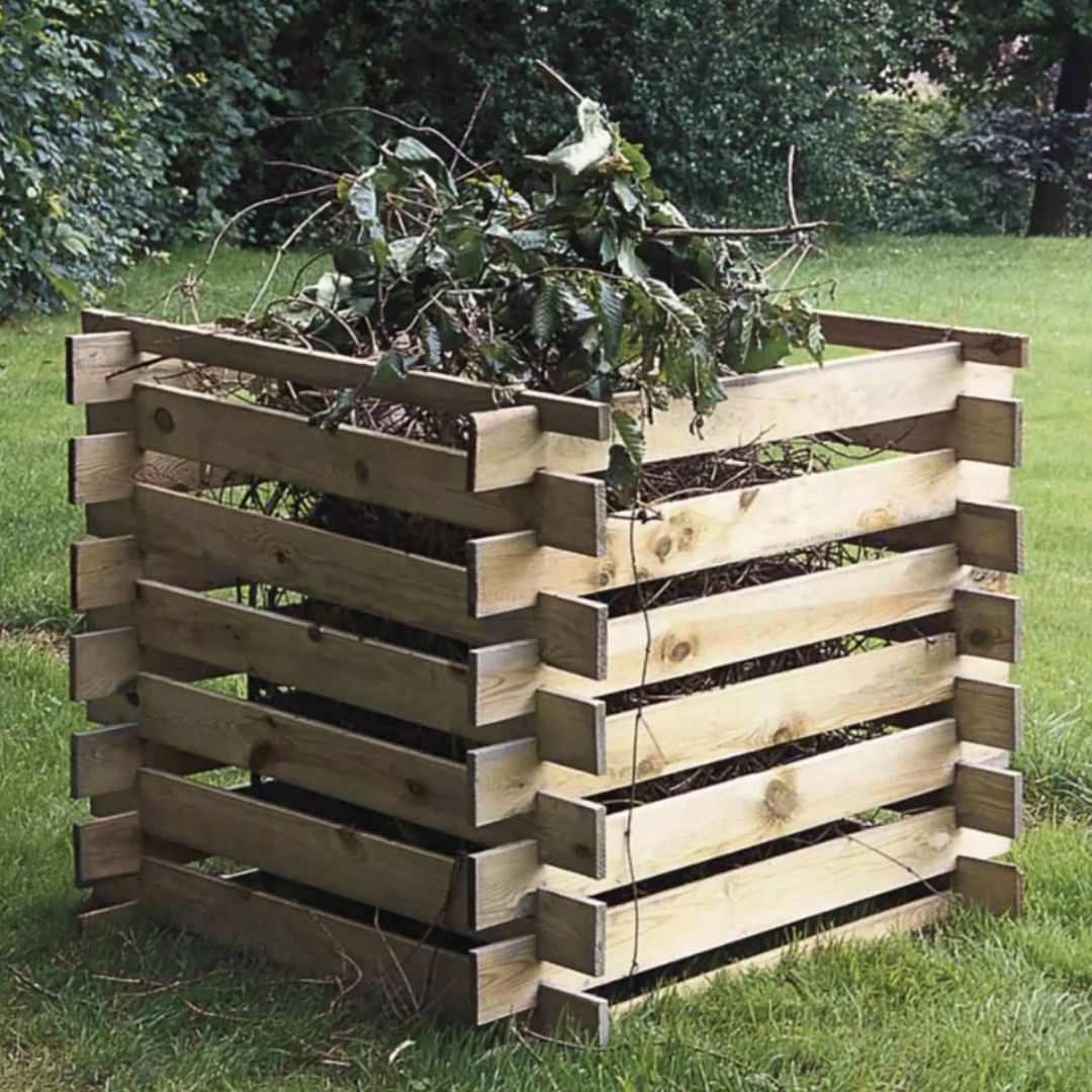 Wooden compost bin filled with garden waste on a grassy area
