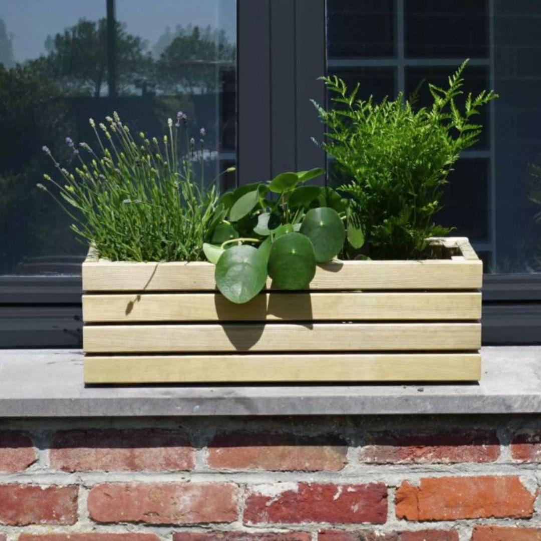 Wooden planter box with plants on a windowsill against a brick wall.