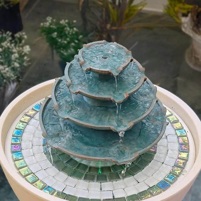 Three-tiered water fountain with mosaic base on a table