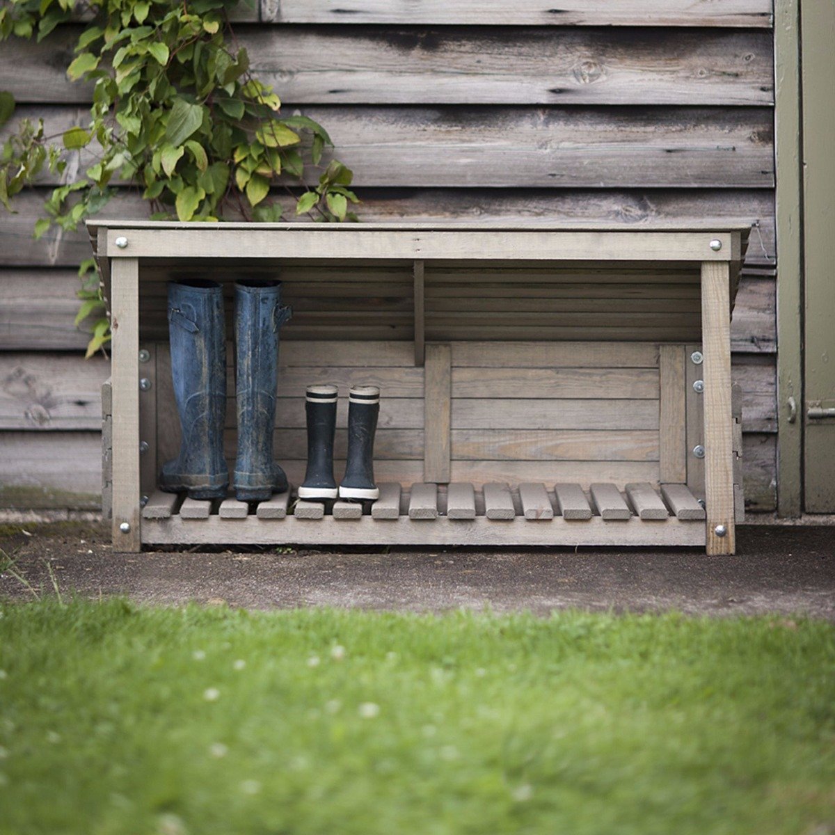 Wooden wellie store in garden with boots in it