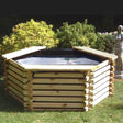 wooden pond in garden sat on grass with bushes in the background