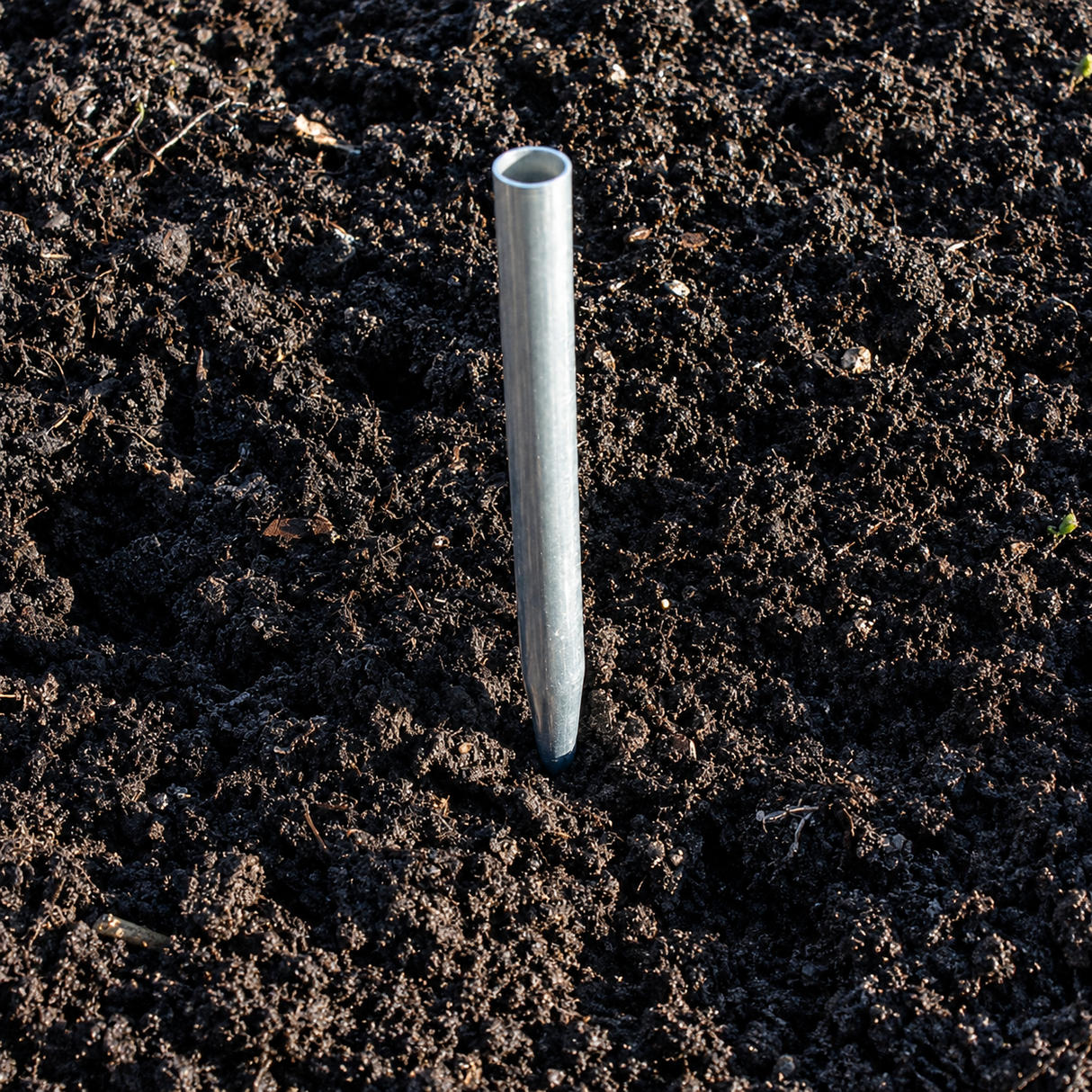 Metal stake driven into dark soil