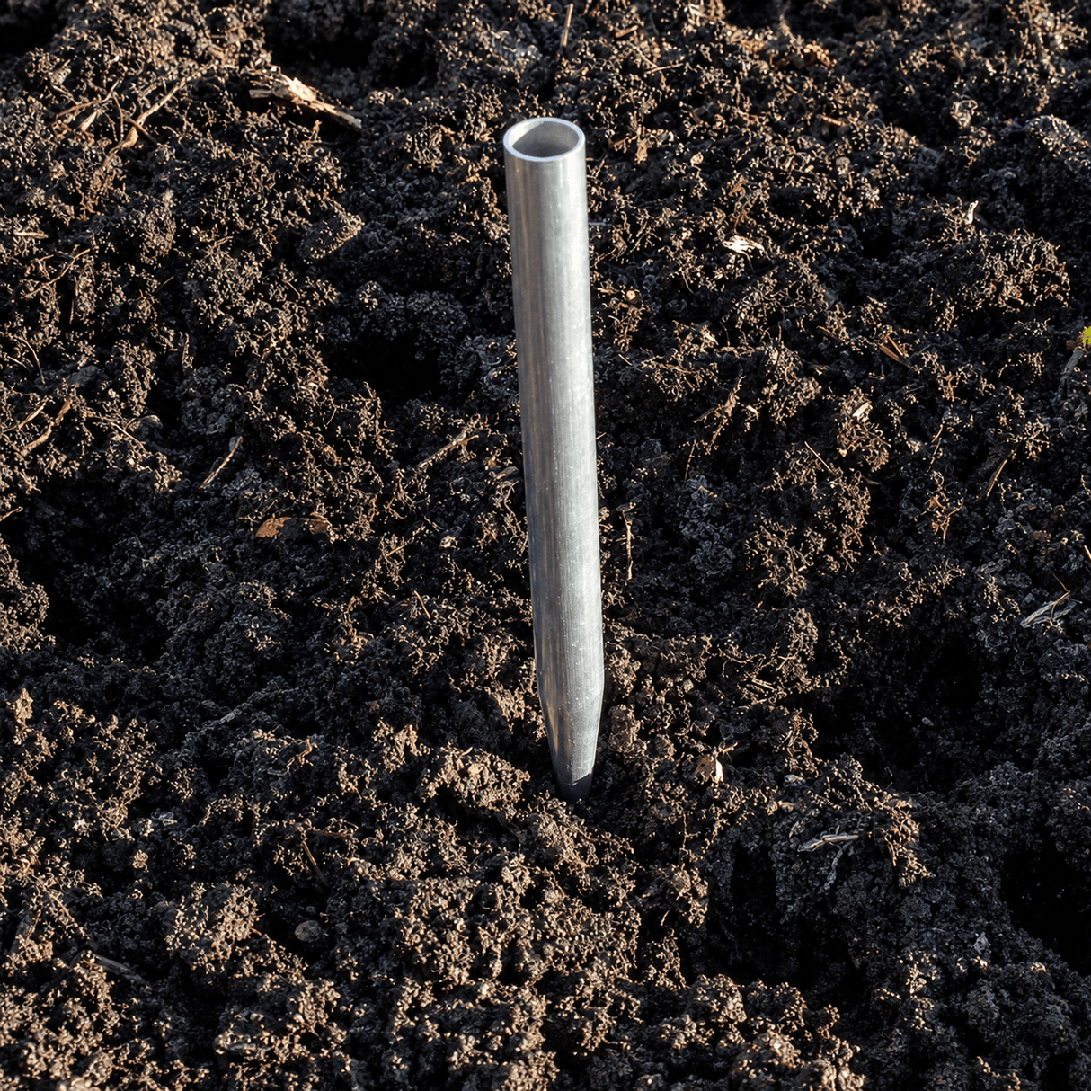Metal stake driven into dark soil