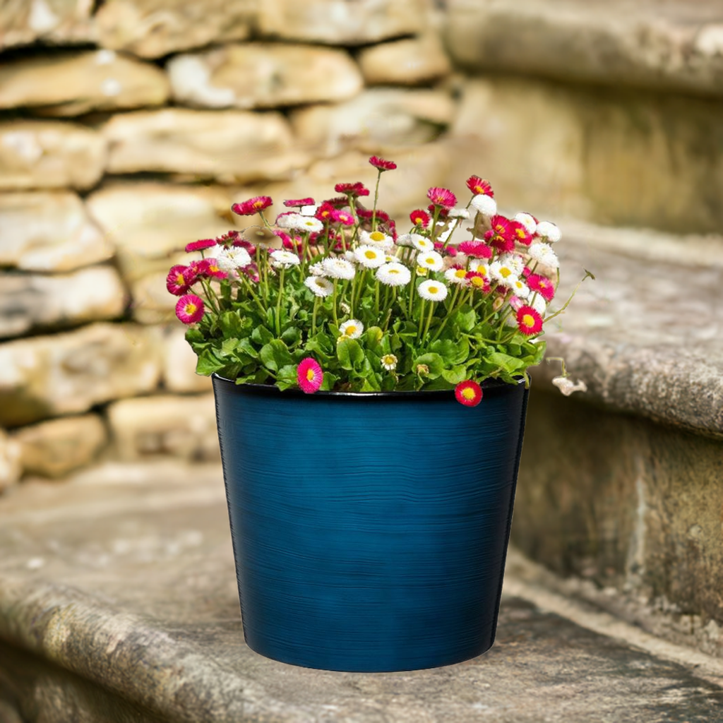 Blue pot with colorful flowers against a stone wall background