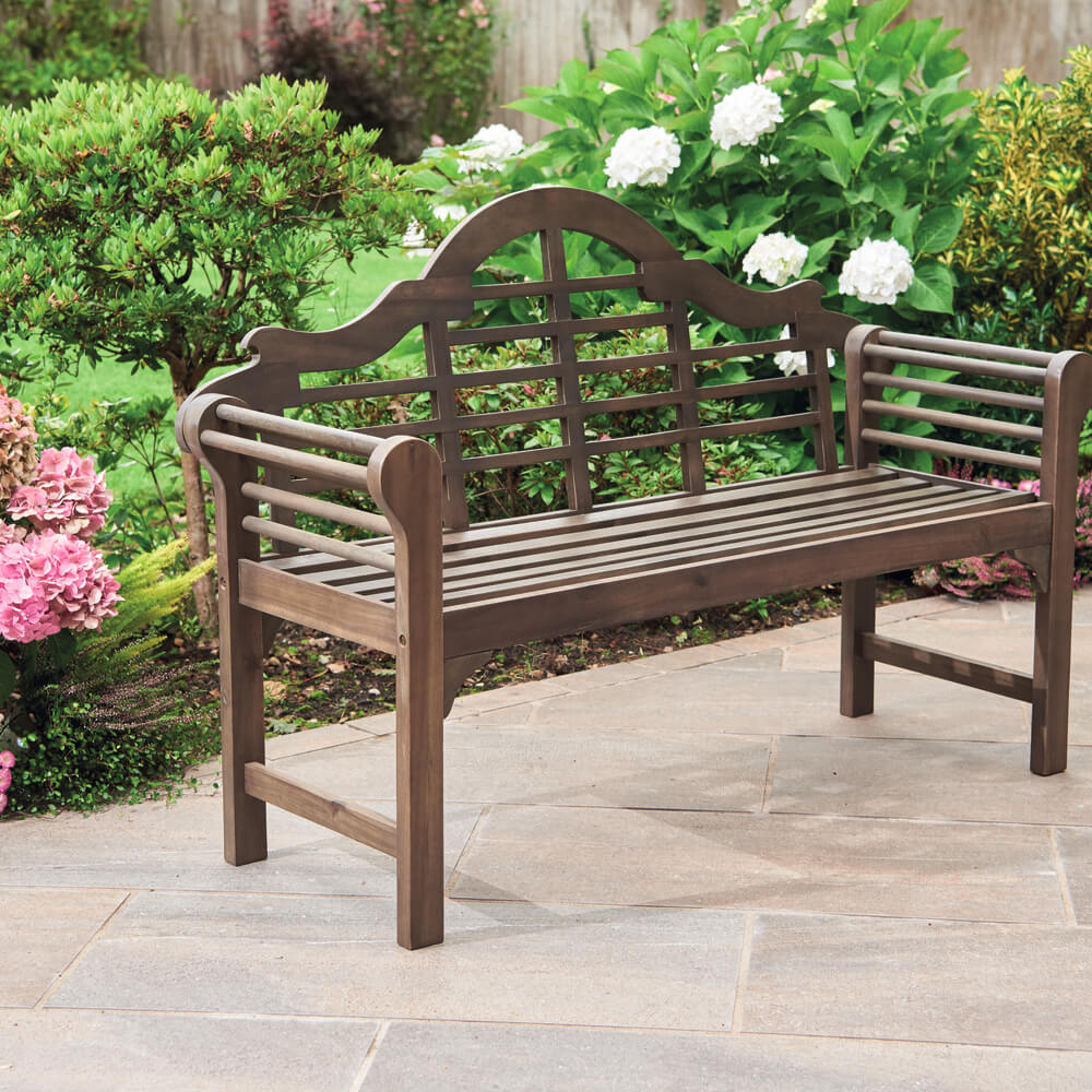 Wooden garden bench in a garden setting with flowers and greenery.