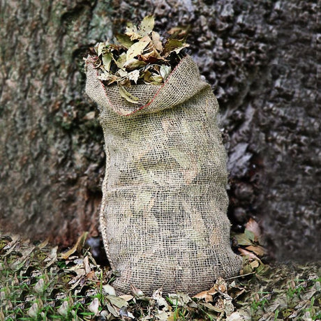 A beige jute composting sack filled with leaves