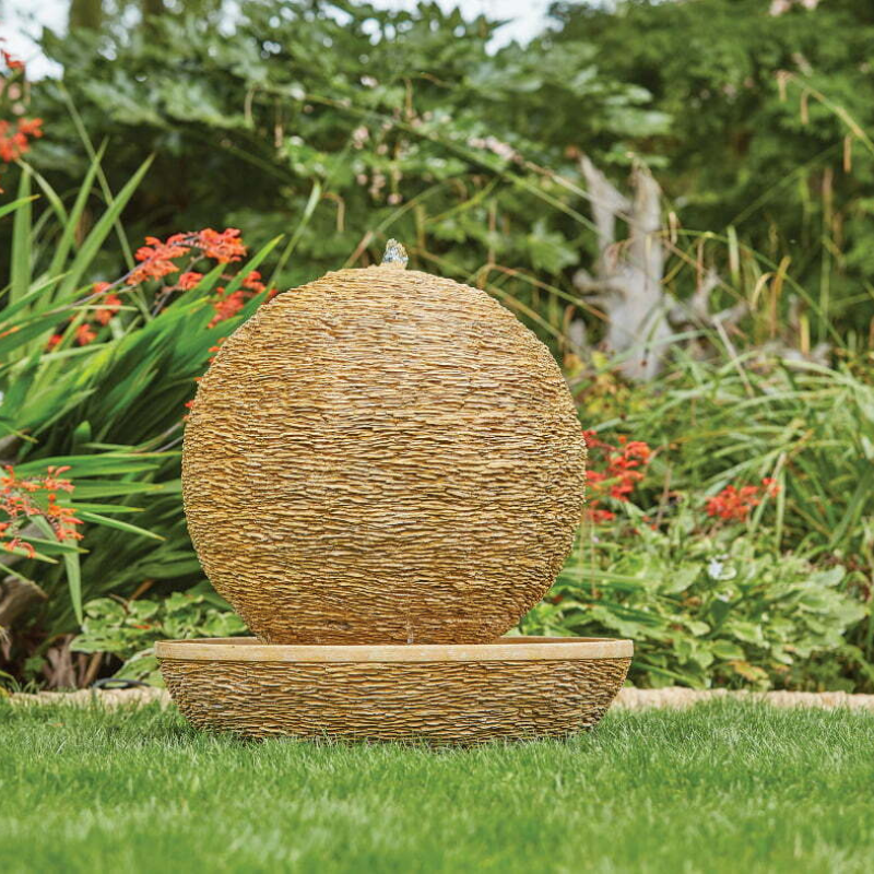 large ball water feature on a stand in a garden setting