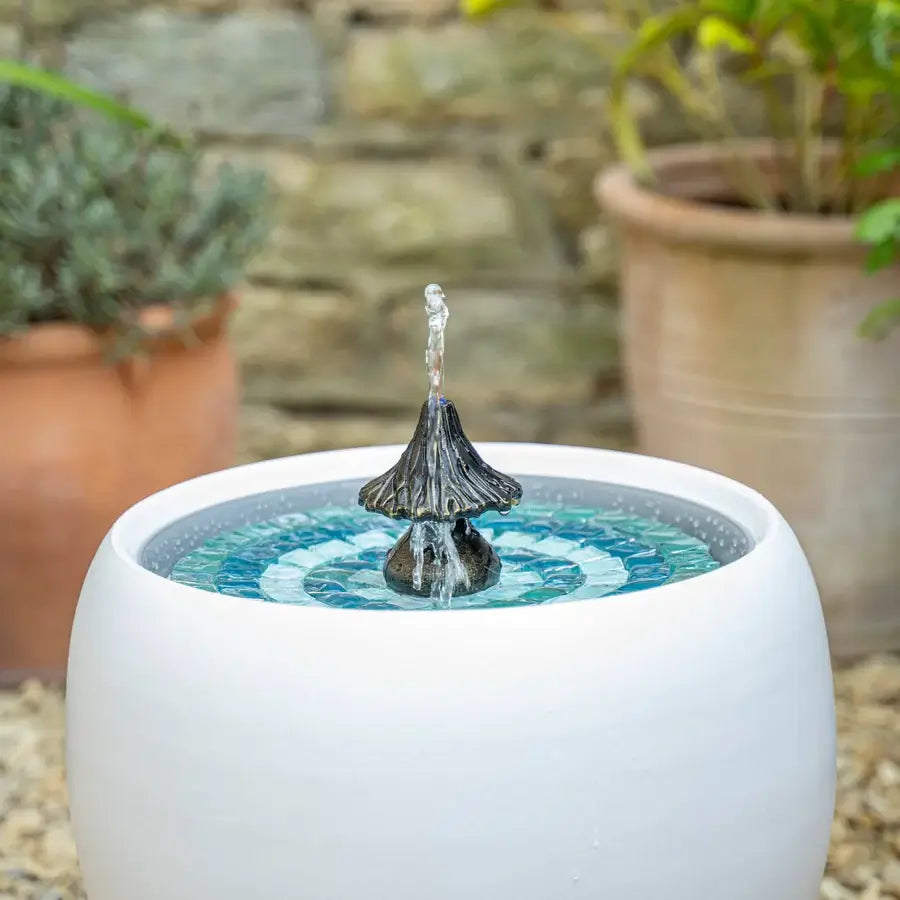 Small water fountain in a white pot