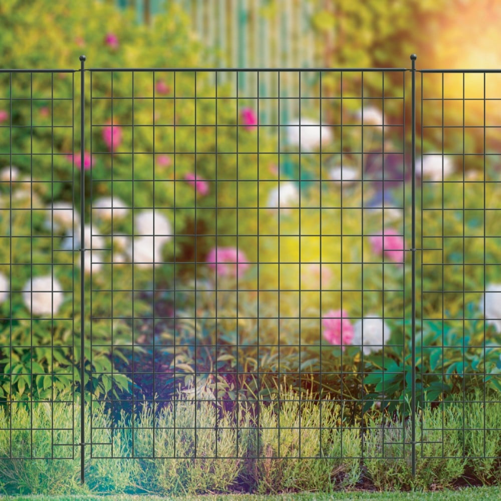 A section of black metal fencing installed in a garden setting, with floral blurred background.