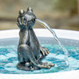 Bronze frog sculpture spouting water into a pool