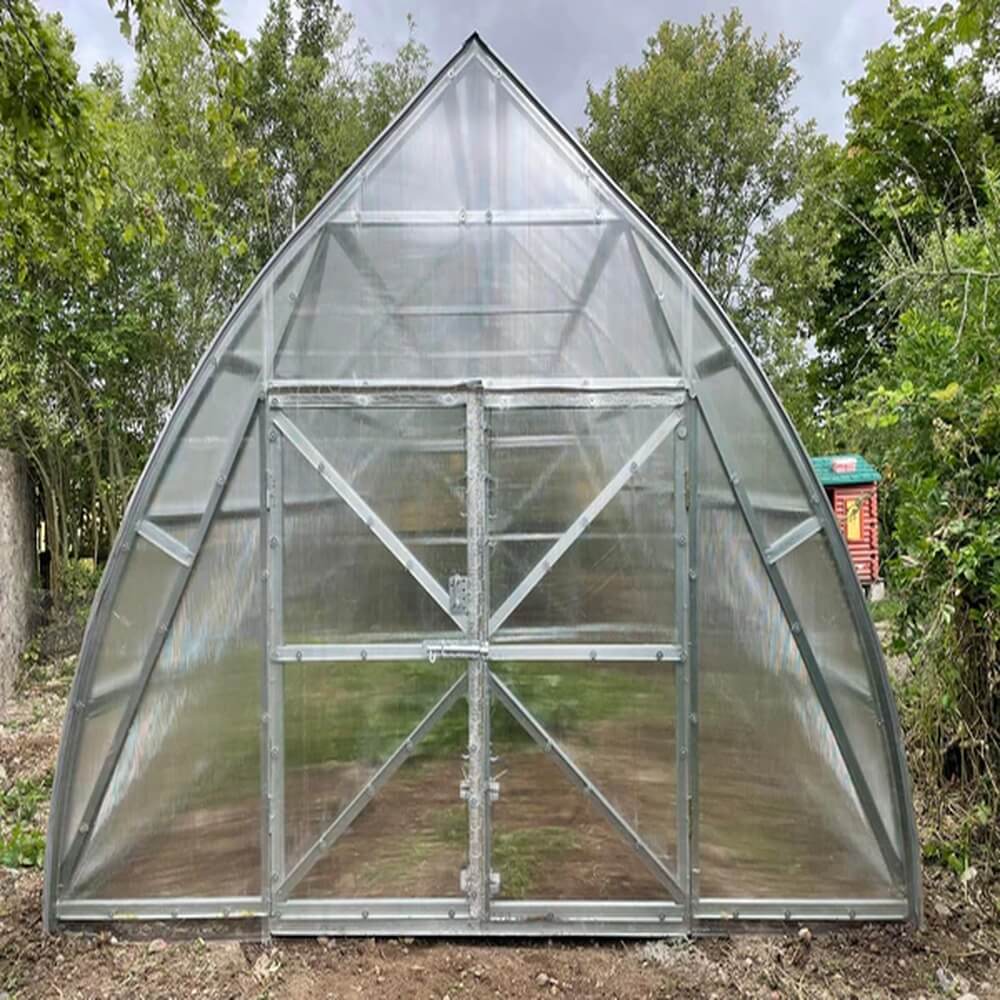 front of a polycarbonate greenhouse with trees