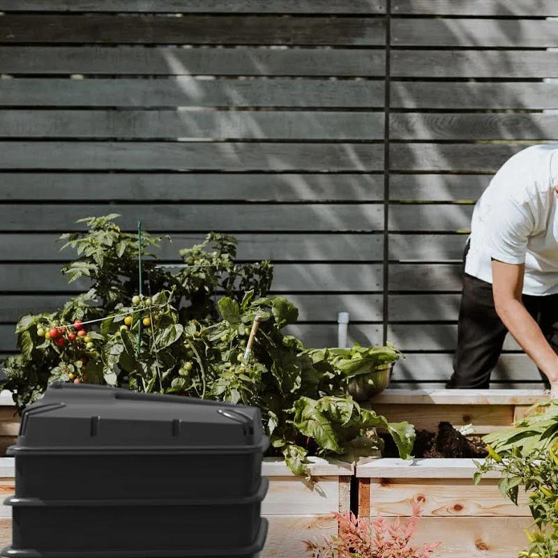 3 tray wormery in garden with someone working in the background