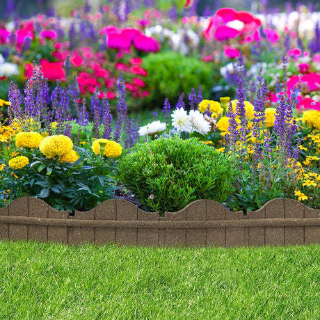 A brown, curved garden border made from recycled rubber, installed around a bed of colorful flowers.