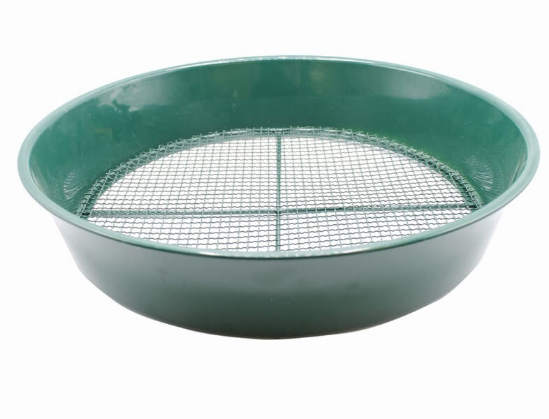 A green metal soil sieve with fine mesh used for sifting and breaking up clumps of soil.