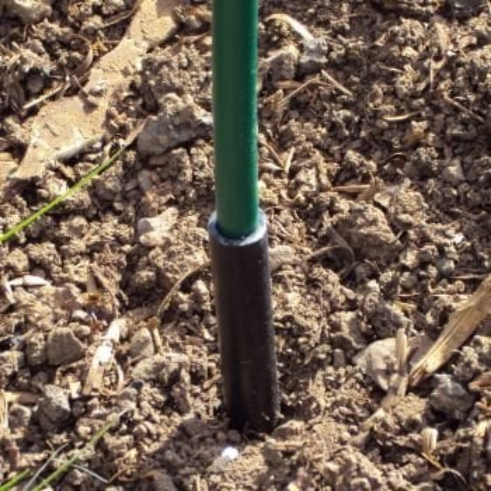 Black plastic anchor tube partially buried in soil