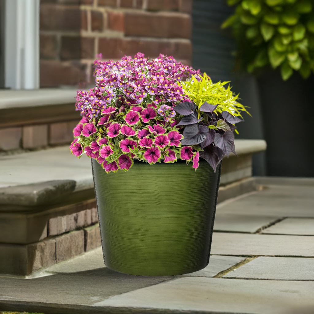 Green pot with colorful flowers on a wooden deck