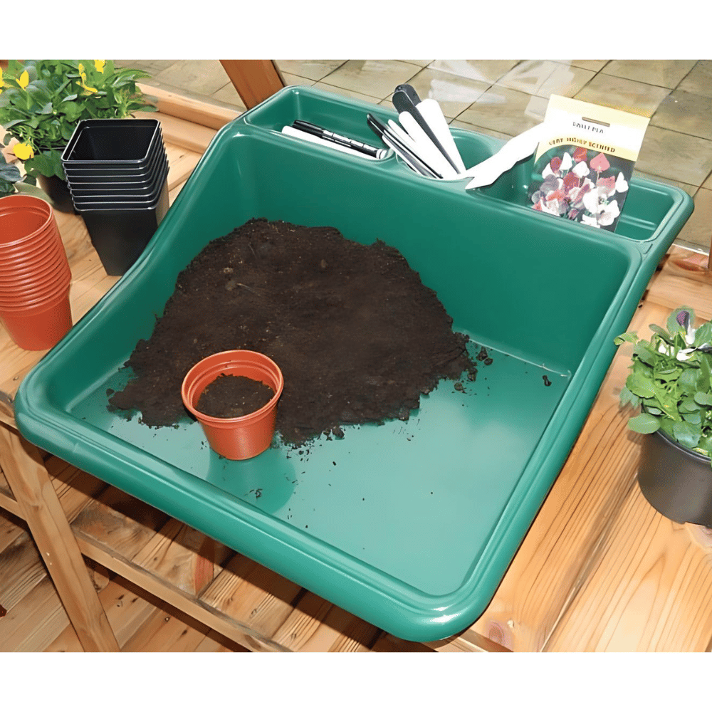 Green potting tray on wooden table with soil and pots
