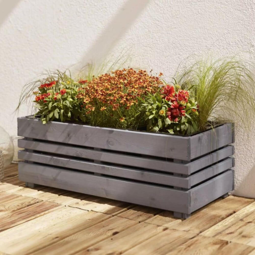 Grey wooden planter box with plants on a wooden deck