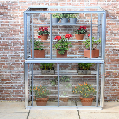 mini greenhouse with sloping roof with plants in it
