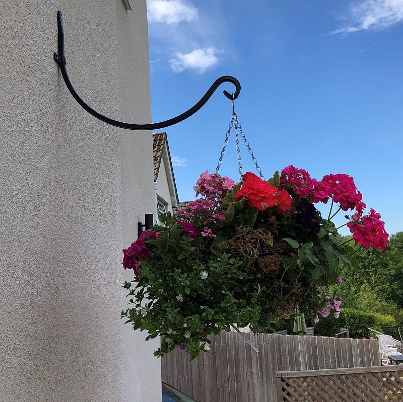 A black metal hanging basket bracket round hook attached to a wall