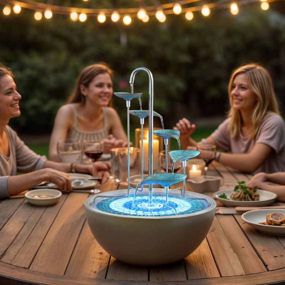 People enjoying a meal around a decorative water fountain at night.