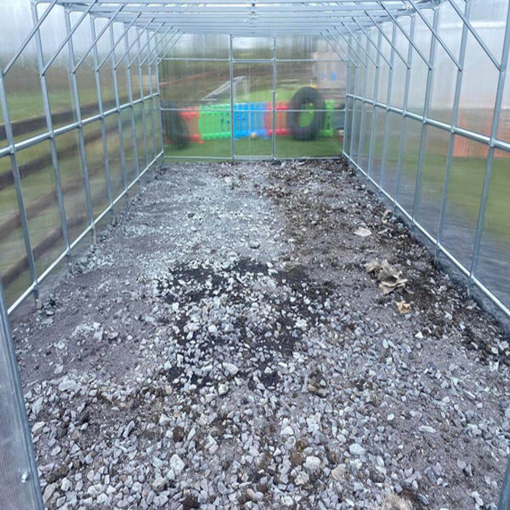 inside of a greenhouse with gravel on the floor