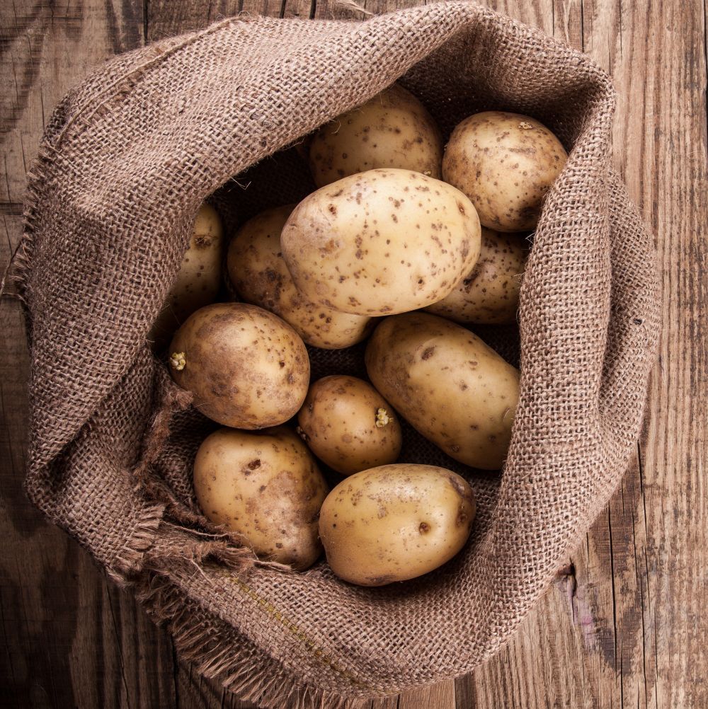 Jute Potato Sack with potatoes in on wooden floor