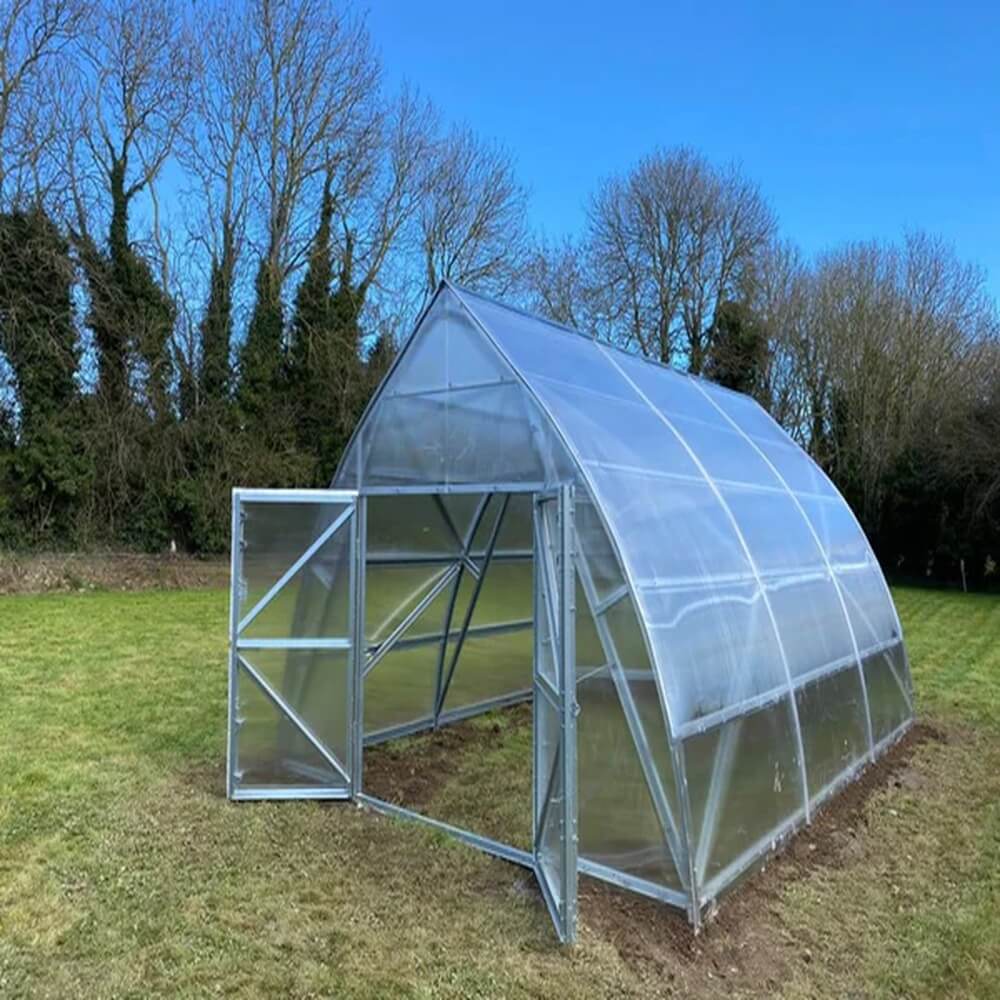 a large polycarbonate greenhouse with trees in the background
