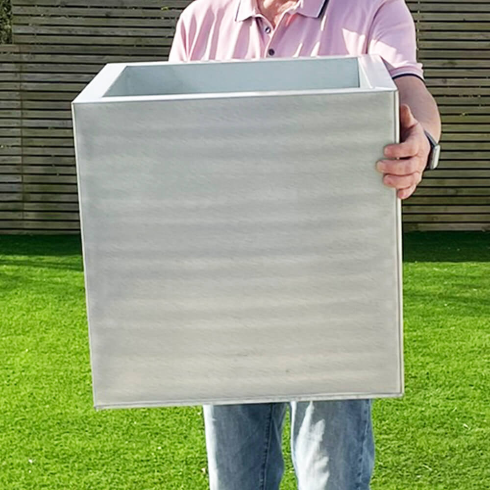 Three silver cube-shaped zinc planters in different sizes, with the smallest in front, medium in the middle, and largest in the back, placed on a patio with plants inside them.