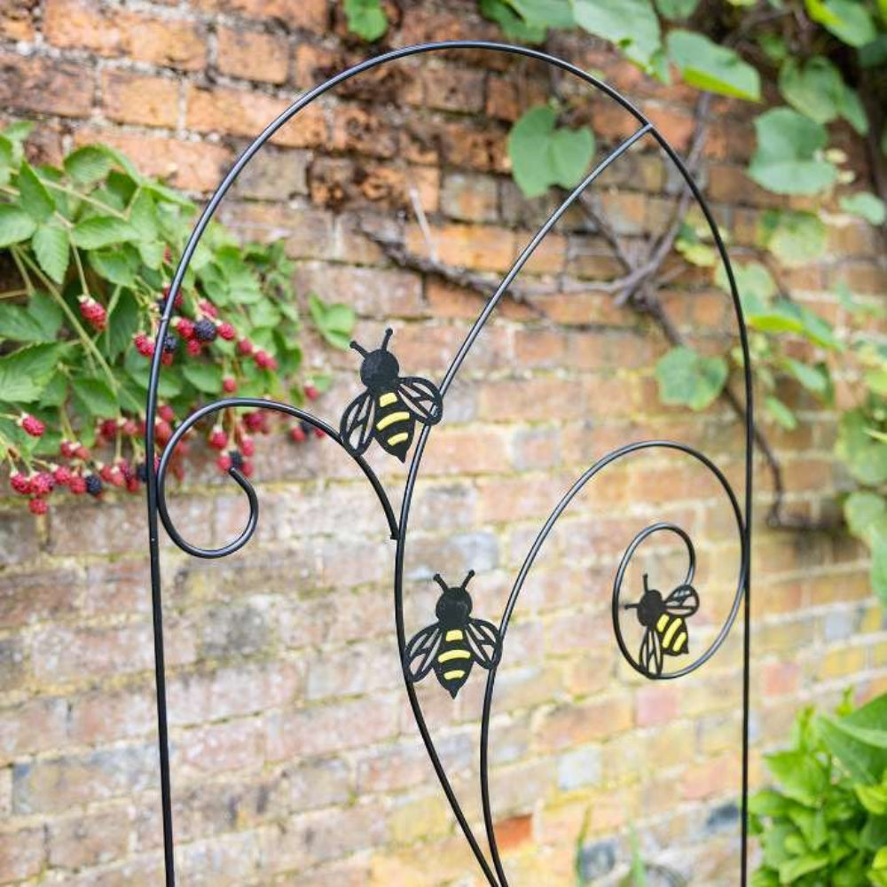 Metal bee trellis in garden infront of wall 3 bees