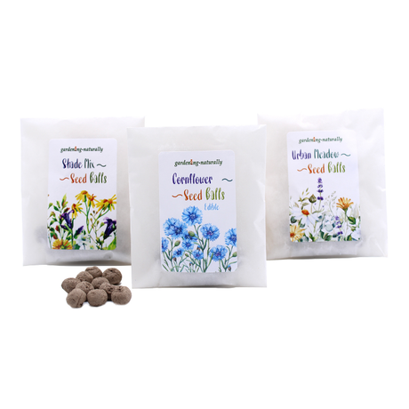 Three packages of wildflower seedballs with labels indicating the type of flowers contained within. Each package displays an illustration of the flowers and a small number of seeds in front.