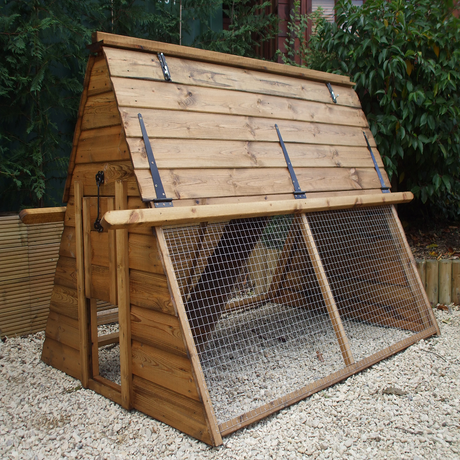 A wooden poultry house with a metal mesh run, designed for chickens, situated outdoors.