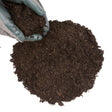 A person's hand holding a scoop of brown organic compost soil.