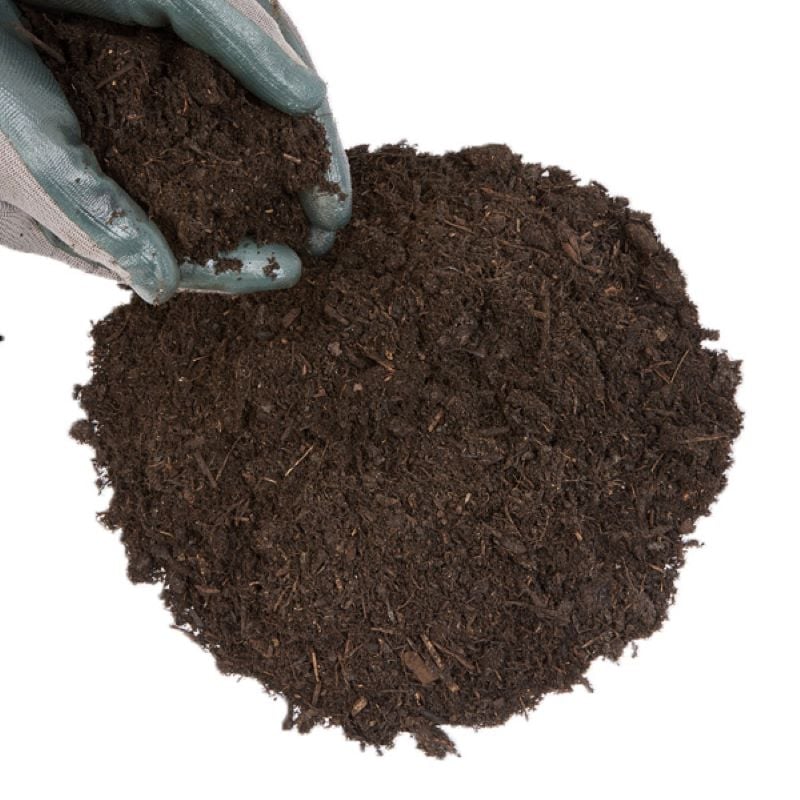 A person's hand holding a scoop of brown organic compost soil.