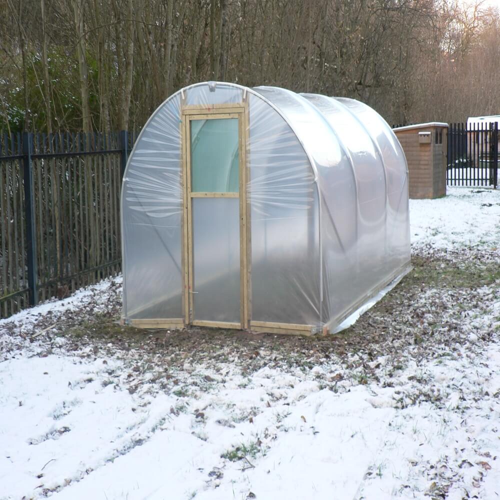 Polycarbonate greenhouse in a snowy backyard setting