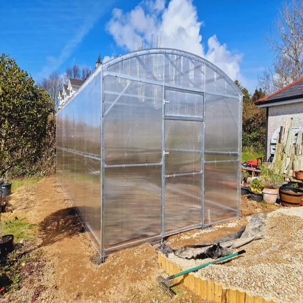 front of a greenhouse in a garden