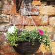 Rattan hanging basket by brick wall with flowers