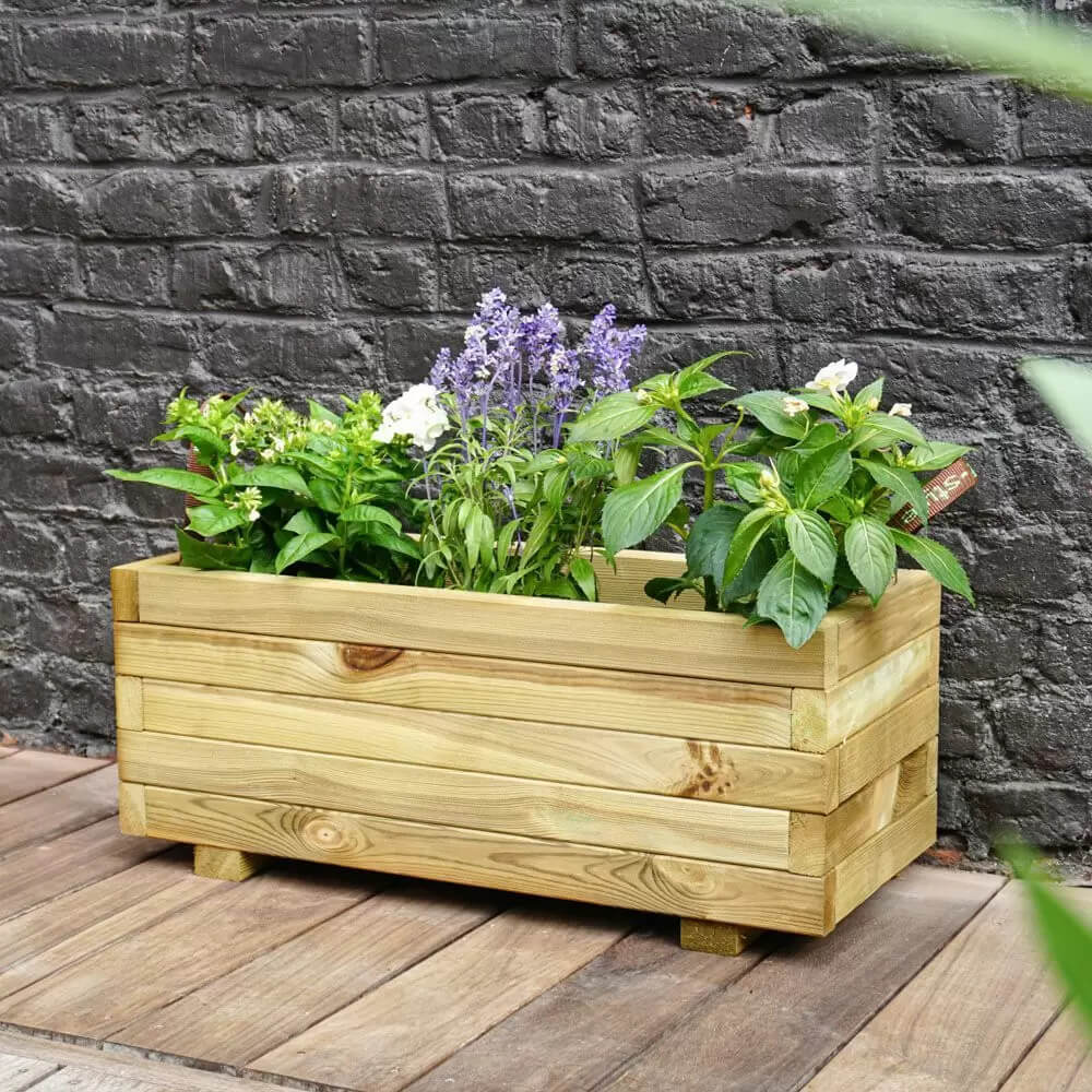 Wooden planter box with plants against a brick wall
