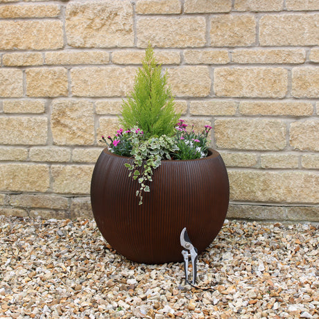 Ridged round planter in garden on gravel