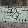 A silver metal 'S' hook attached to a black mesh netting
