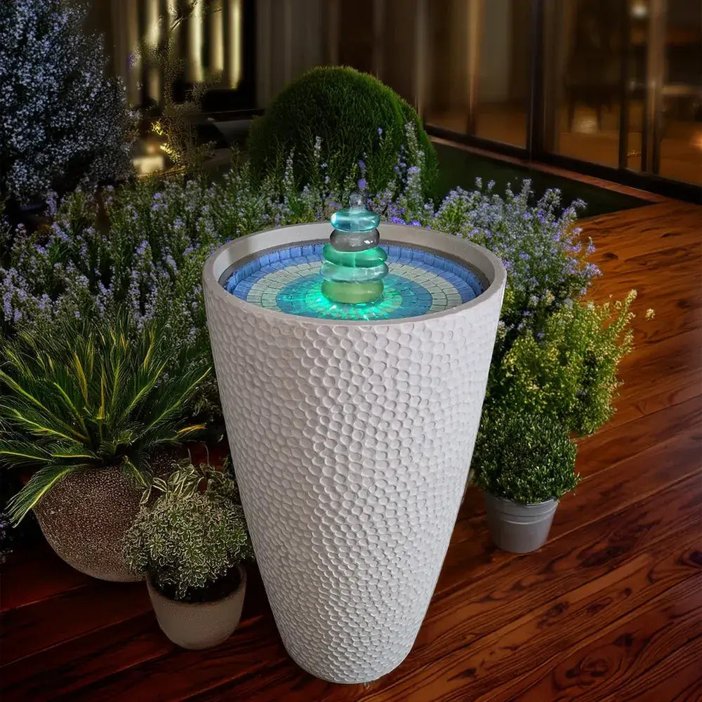 Decorative outdoor fountain with mosaic design on a wooden deck surrounded by plants