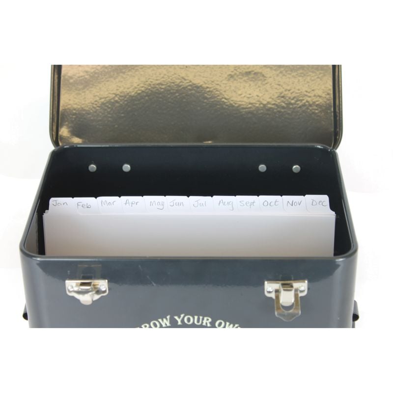 A set of white paper dividers with monthly labels, placed inside a black metal seed tin with a lid.