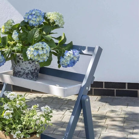 Grey and white shelving with plants in garden