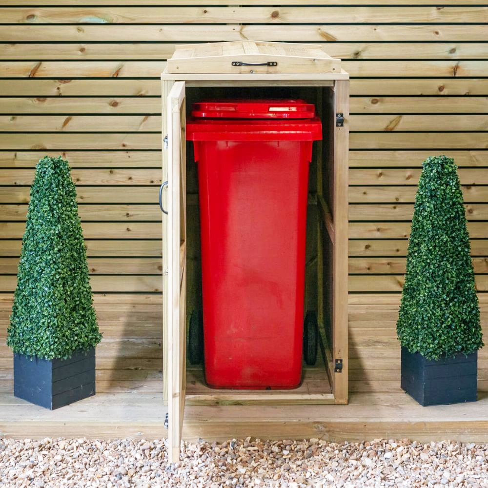 A single wooden wheelie bin storage unit with a red bin visible, placed on a gravel surface, flanked by two artificial green shrub pots.