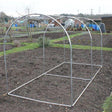 An aluminium hoop frame structure set up on a garden plot, designed for protecting fruit bushes, trees, or vegetables.